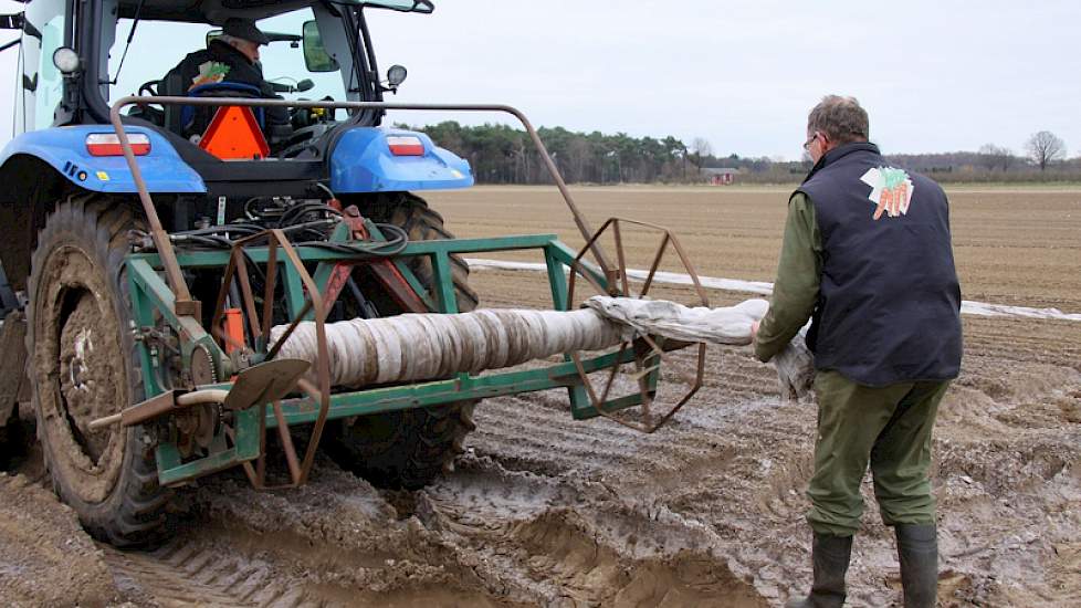 Terwijl de trekker langzaam doorrijdt, trekt Huub in ’t Zandt de folie van de rol. Na het zaaien wordt de rug afgedekt met folie om de teelt te vervroegen. Op dit perceel is het ras Napoli gezaaid.