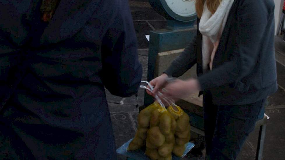 Een vrijwilligster weegt aardappelen af voor een klant in de Der Aa-kerk.