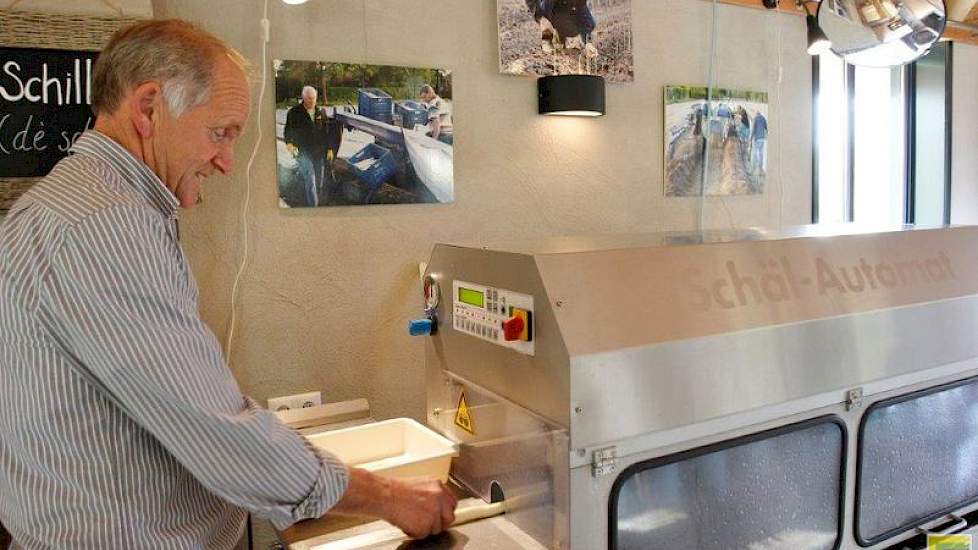 Met de schilmachine schilt hij asperges voor de verkoop in zijn winkel.