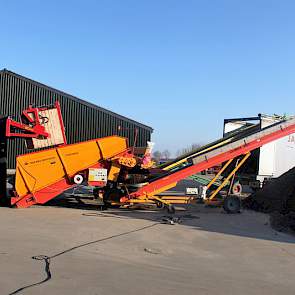 De stortbak met opvoerband richting vrachtauto en de transportband voor de afvoer van grond staan opzij van de bewaarloods.