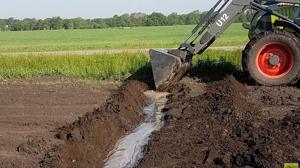 Met de trekker graaft akkerbouwer Johan Emmens geulen om het water zo snel mogelijk van het land te krijgen.