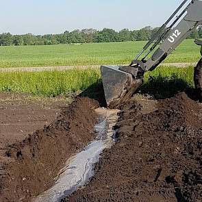 Met de trekker graaft akkerbouwer Johan Emmens geulen om het water zo snel mogelijk van het land te krijgen.