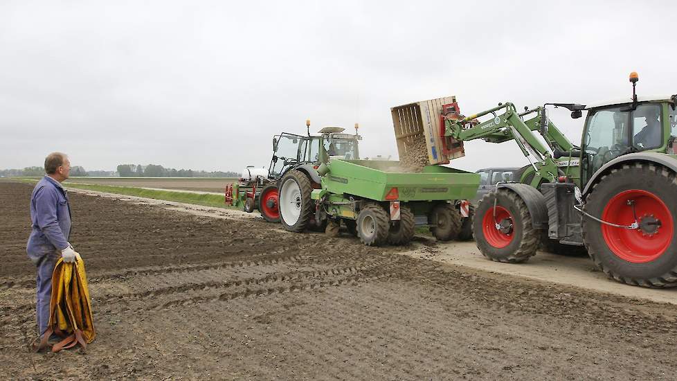 Ko Scholtens wacht met een opvangzeil in de hand om de pootmachine leeg te kunnen maken en vervolgens een nieuw ras te kunnen gaan poten. Wat Scholtens betreft mag het net als afgelopen jaar wel weer een droog seizoen worden. „We zijn hier wel tegen de dr