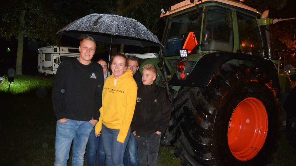 De familie Gunnik uit Alteveer (DR) staat met vijf man achter een trekker te schuilen onder een grote paraplu. Zoon Karlo (links) en zijn vriendin Laurien Kremer (gele trui) stappen straks in de trekker, zijn ouders en broertje zwaaien hen uit. „We moeten