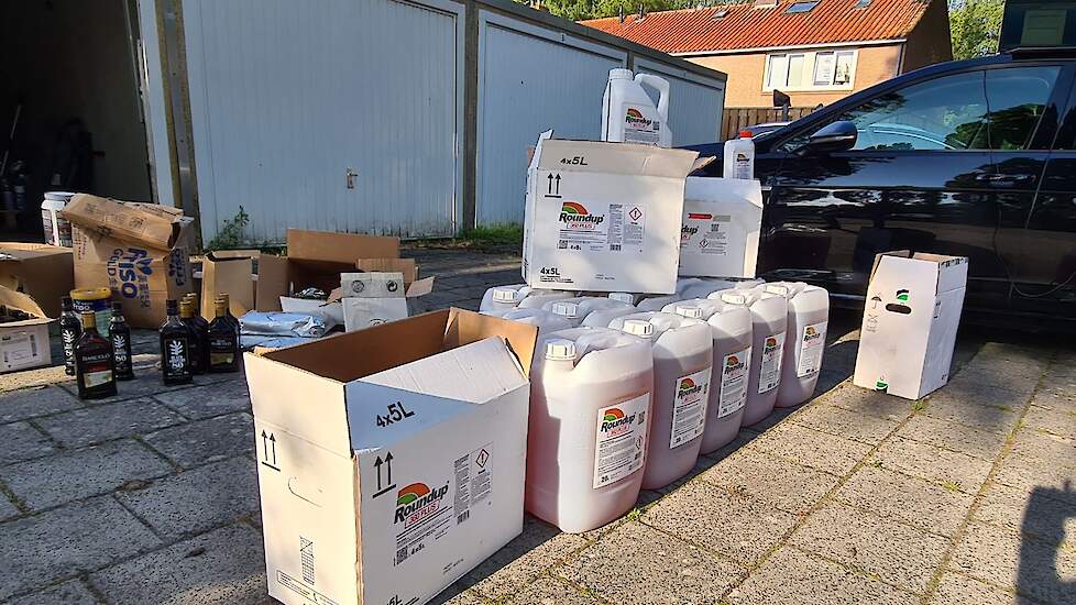 De in beslag genomen vaten Roundup en flessen alcohol.