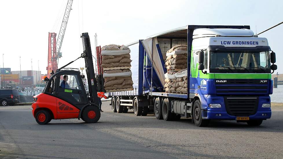 Met vrachtwagens worden de zakken met pootaardappelen aangevoerd. Deze worden op het haventerrein vlak bij de boot gelost.