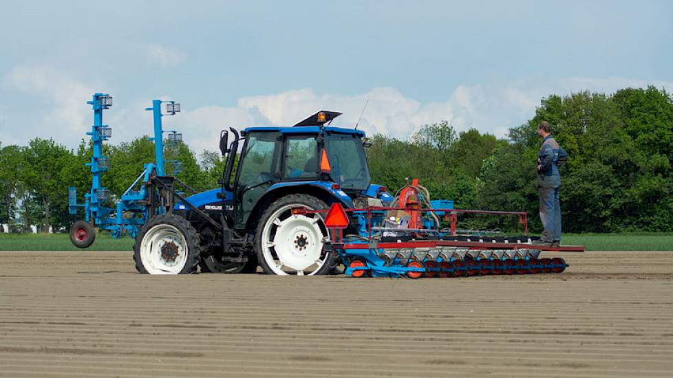 Witlof zaaien gebeurt met twee personen. Achterop de machine staat een tweede man, die zich enkel en alleen bezig houdt met de zaaimachine.
