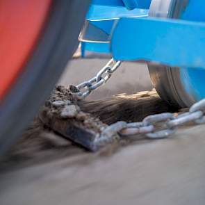 Na deze rol een ijzeren stripje met lichte V-vorm, gehangen aan 2 kettinkjes. Deze dekken het zaad weer toe. Links in beeld is de brede aandrukrol te zien, welke de rug weer netjes verdicht.