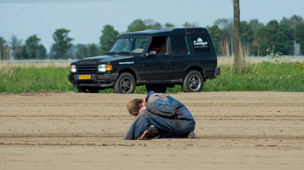 Piet stapt van de machine af om te kijken of het zaad goed wordt verzaaid.