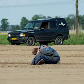 Piet stapt van de machine af om te kijken of het zaad goed wordt verzaaid.