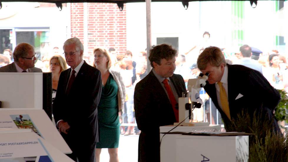 Eric Casteleijn (directeur NAK) geeft uitleg over grondonderzoek terwijl koning Willem Alexander door de microscoop kijkt.