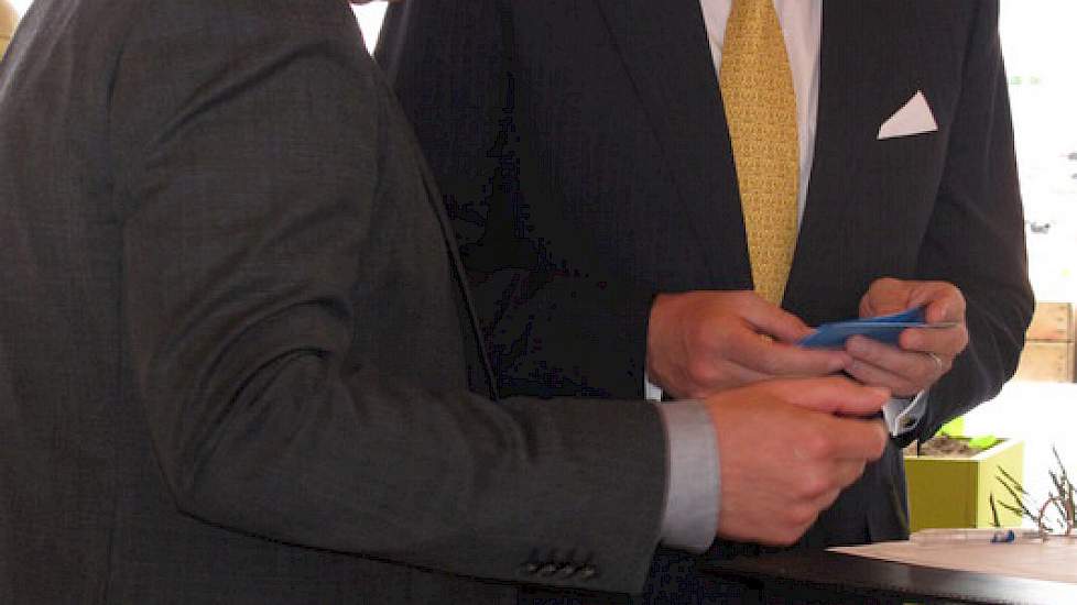Directeur Eric Casteleijn van de NAK biedt de koning speciale certificaten aan met daarop de namen van de vrouw en dochters van de koning.